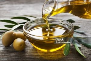 bottle pouring virgin olive oil in a bowl close up